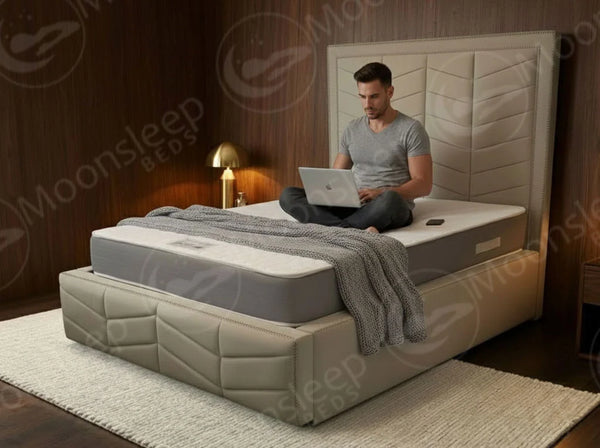 Man using a laptop on a Moonsleep mattress in a bedroom setting